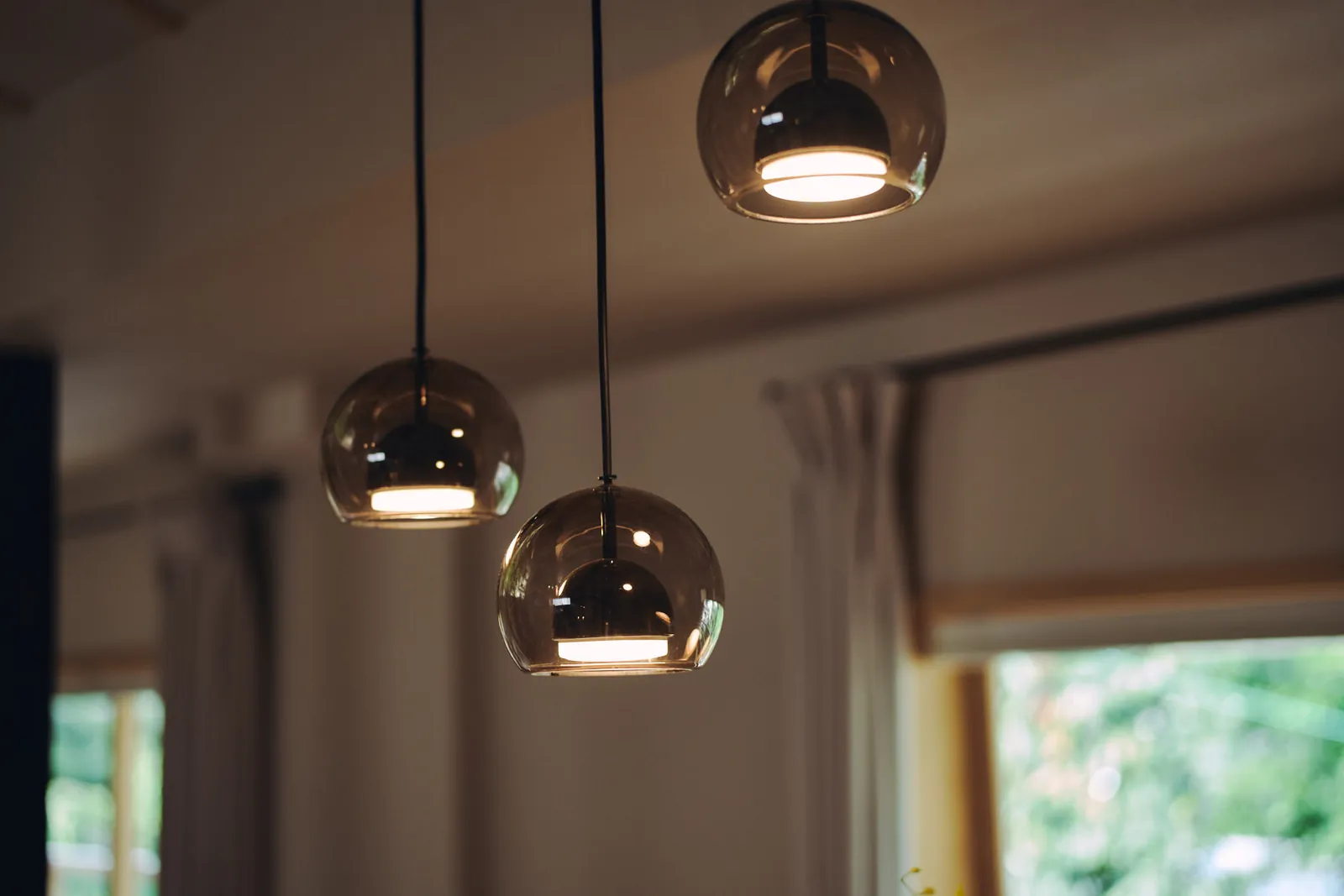 ダイニングを照らすガラスのペンダントライト / Smoked-glass pendant lights above the dining table