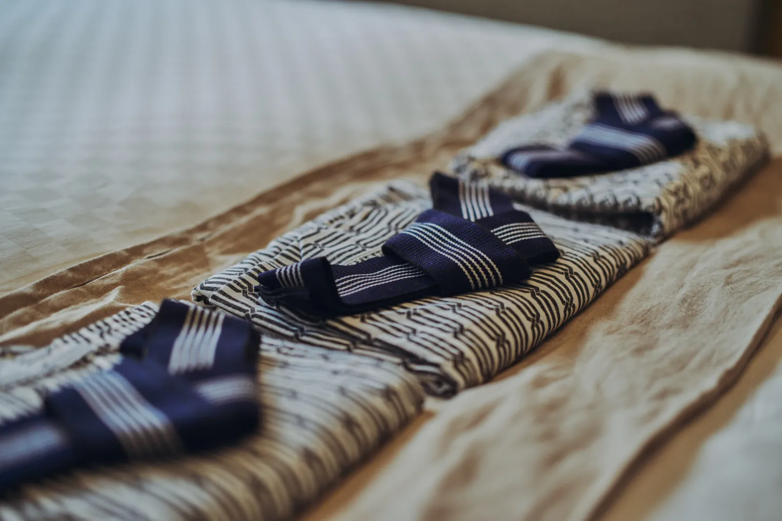 ベッドに並べて用意された浴衣と帯 / Yukata robes and obi sashes laid out on the bed for guests